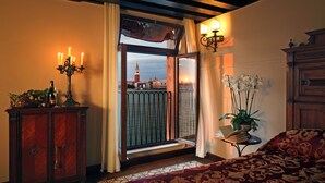 A hotel room with a view of a tower, a wooden cabinet, a bedside table with a plant, and a patterned bedspread. - Bauer Palladio Hotel & Spa (Venice)