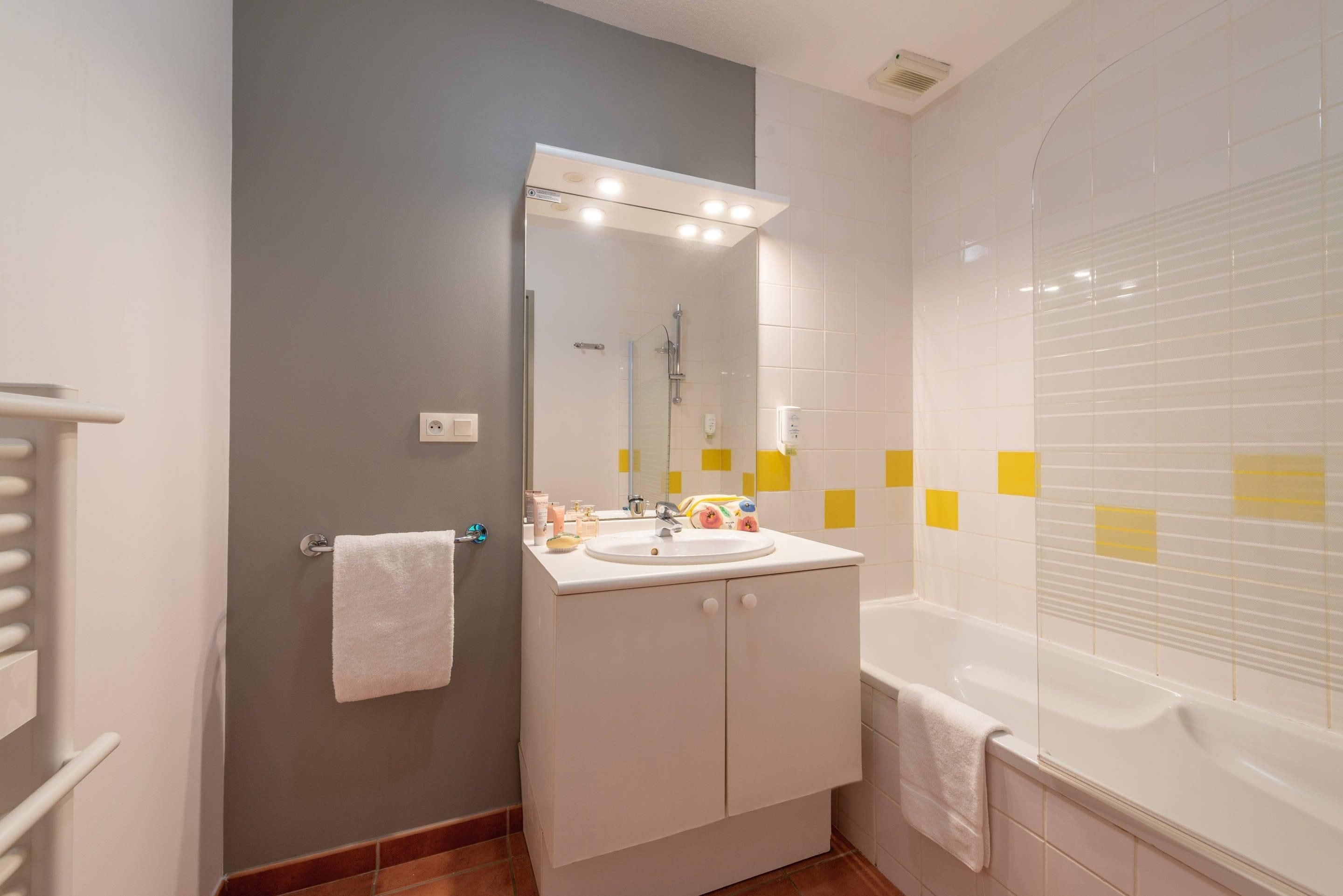A bathroom with a white sink, mirror, and bathtub.