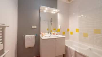 A bathroom with a white sink, mirror, and bathtub.