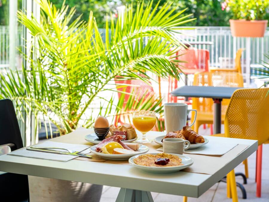 A breakfast table with plates of food, a glass of orange juice, and a croissant.