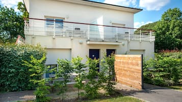 Een modern huis met twee verdiepingen, een balkon, een garage en een houten omheining.