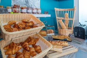 A bakery display with baskets of croissants and baguettes, jars of honey, and a toaster. - Comfort Aparthotel Nantes La Beaujoire (Nantes)