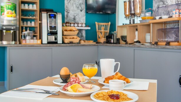 A breakfast setup with eggs, croissants, and orange juice on a table. - Comfort Aparthotel Nantes La Beaujoire (Nantes)
