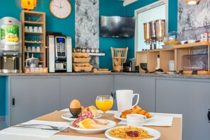 A breakfast setup with eggs, croissants, and orange juice on a table. - Comfort Aparthotel Nantes La Beaujoire (Nantes)