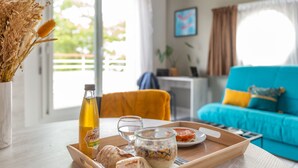 A dining table with a tray containing bread, a glass of water, a bottle of juice, and a jar of spread. - Comfort Aparthotel Nantes La Beaujoire (Nantes)