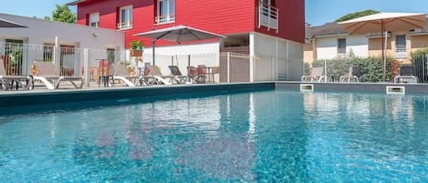 Una piscina al aire libre de temporada, sombrillas