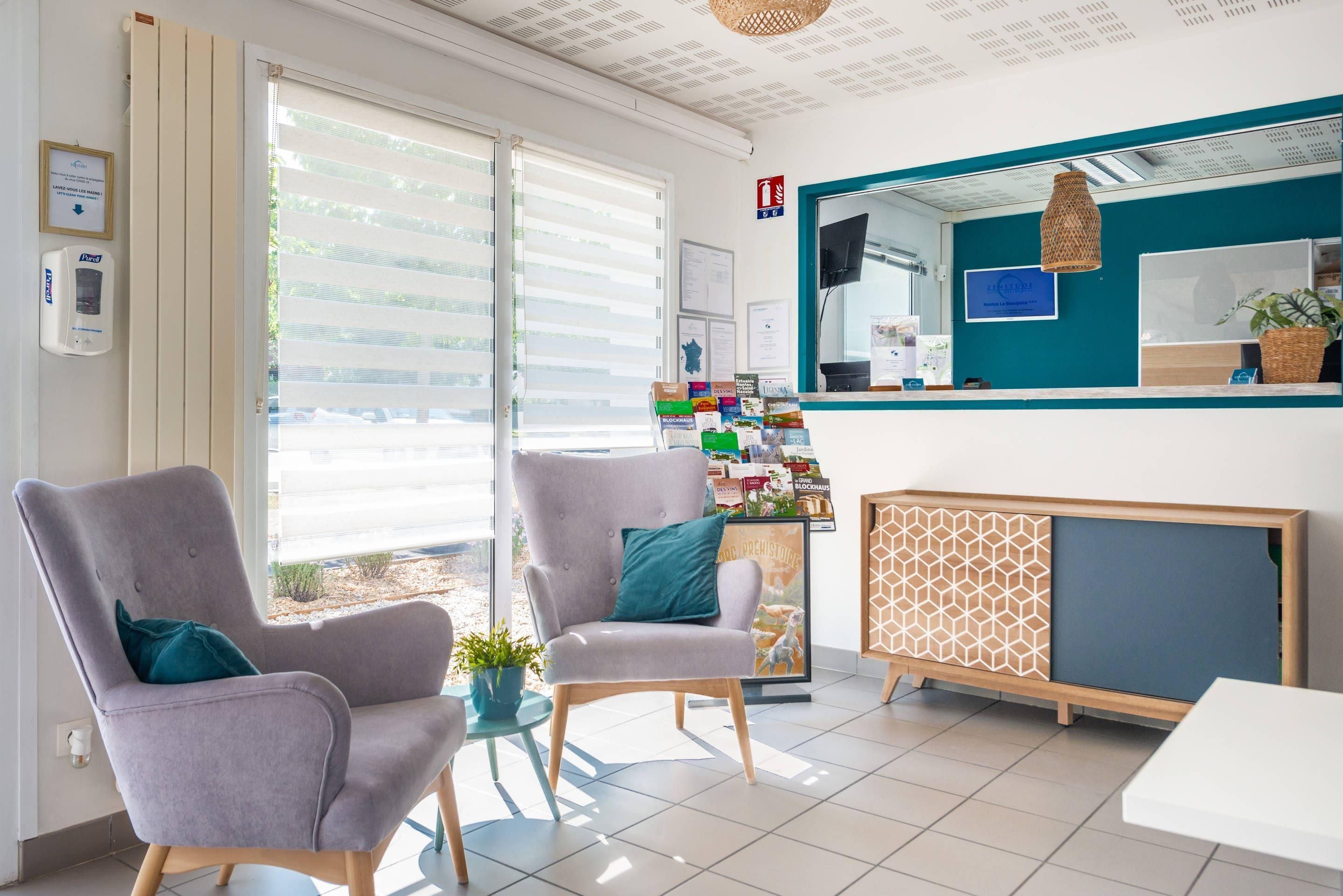 A reception area with a counter, two armchairs, a small table, and a potted plant.