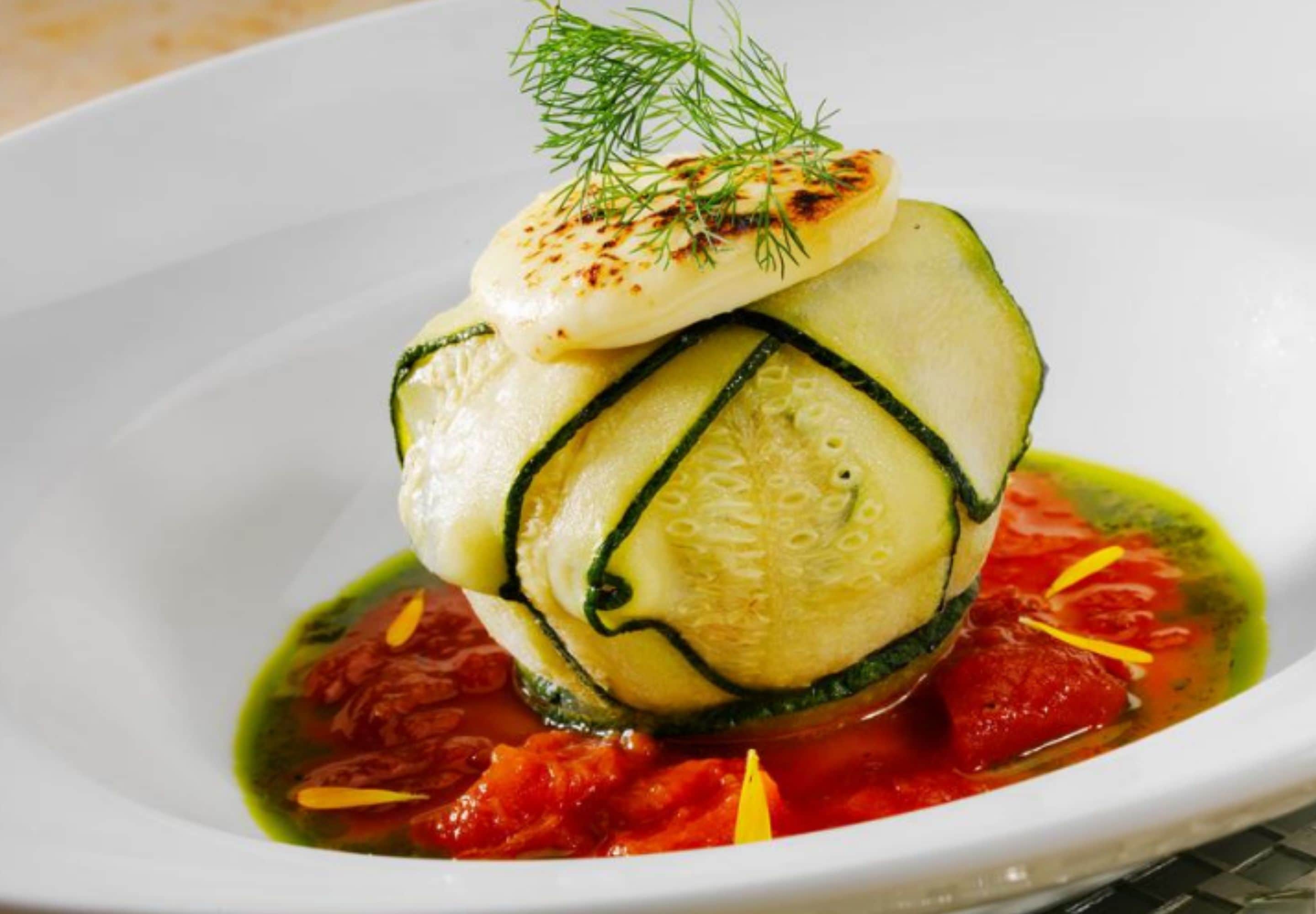 A dish with zucchini and a dollop of sauce, garnished with dill.