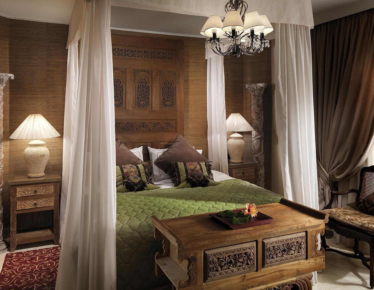 Un dormitorio con cama con dosel, un cabecero ornamentado y una mesita de noche de madera con lámpara.