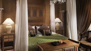 Un dormitorio con cama con dosel, un cabecero ornamentado y una mesita de noche de madera con lámpara.