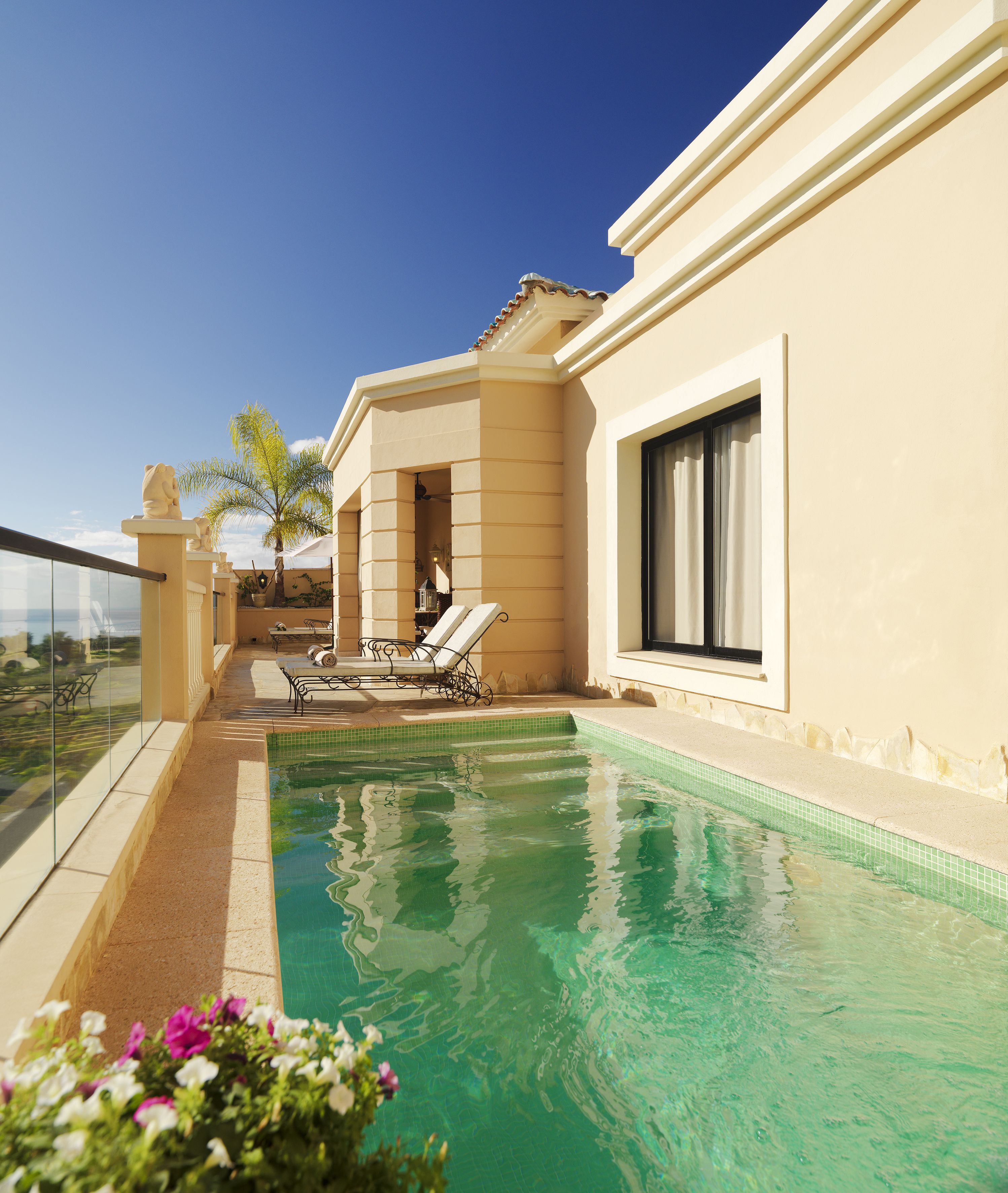 Une piscine dotée de chaises longues, d’une balustrade en verre et offrant une vue dégagée sur le ciel.