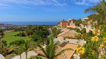 Un complejo turístico costero con edificios de tejas color terracota, palmeras y vistas al océano.