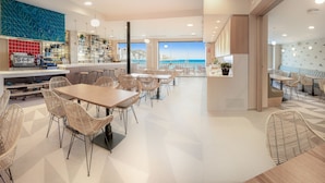 Un restaurante moderno con zona de bar, diversas opciones de asientos y vistas al mar.