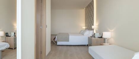 A hotel room with two beds, a wooden wardrobe, bedside tables with lamps, and a patterned wall.