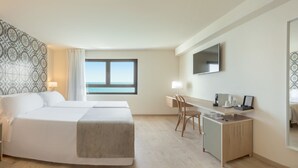 Habitación de hotel con cama, escritorio, silla, televisión y ventana con vistas.