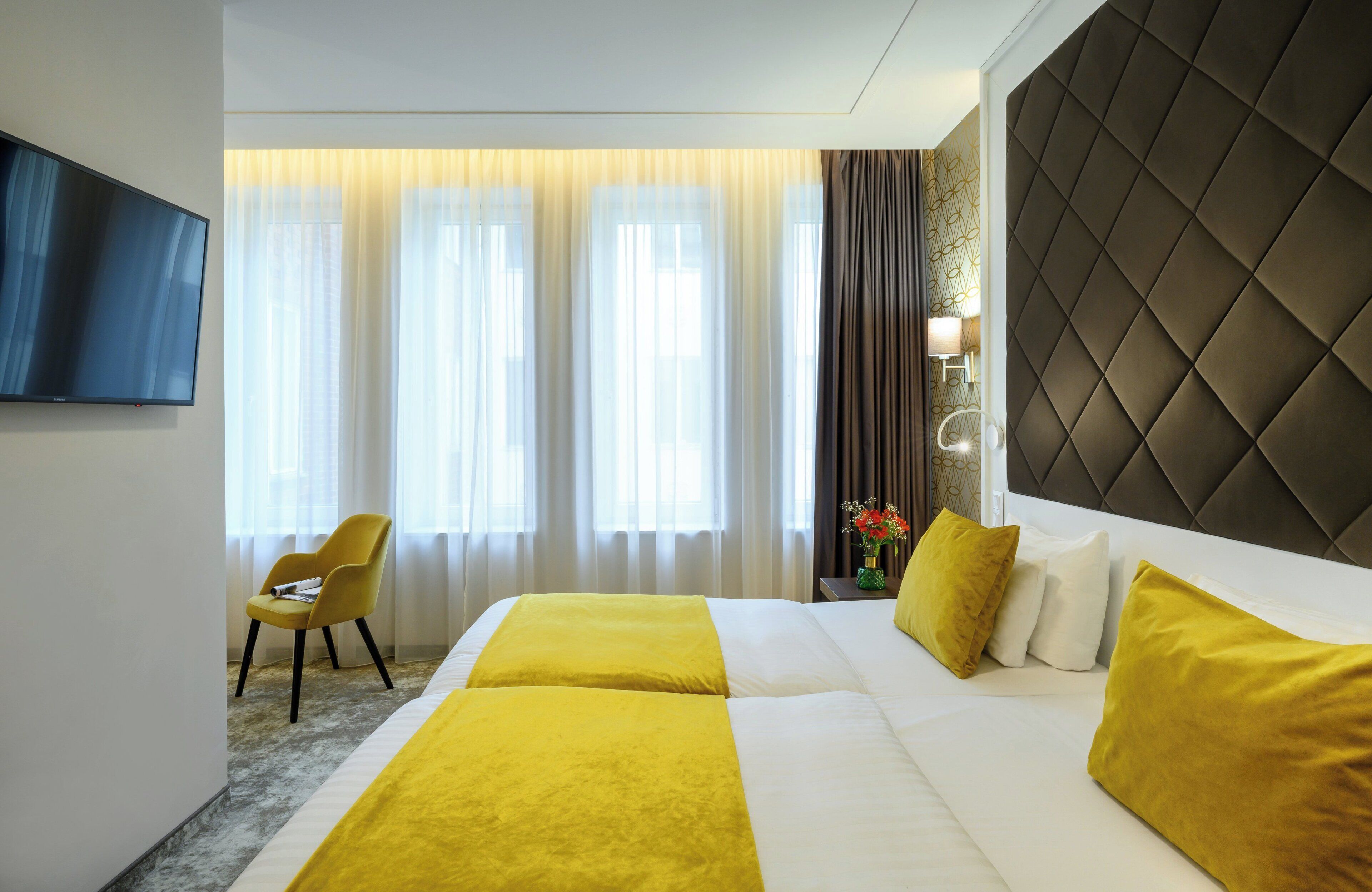 Una habitación de hotel con una cama grande, televisión y una silla.