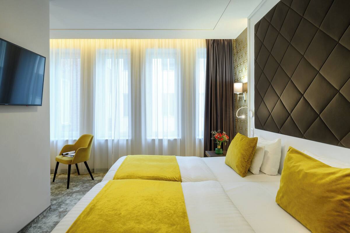 A hotel room with a large bed, a TV, and a chair.