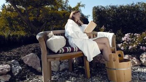 A person sitting on a wooden bench outdoors with a book, surrounded by rocks and greenery. - Alpine Wellfit Hotel Eagles-Astoria (Innsbruck)