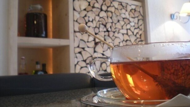 Una taza de té con una bolsita de té sobre un platito, sobre una mesa.