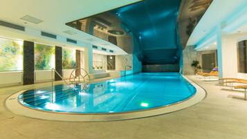 An indoor swimming pool with a curved ceiling and a clear water surface.