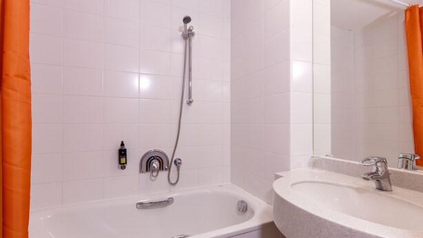 Un baño con bañera, ducha y lavabo con espejo.