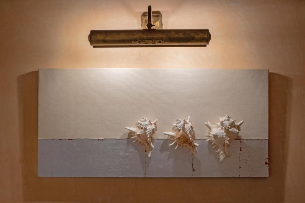 A wall-mounted artwork with three abstract sculptures.