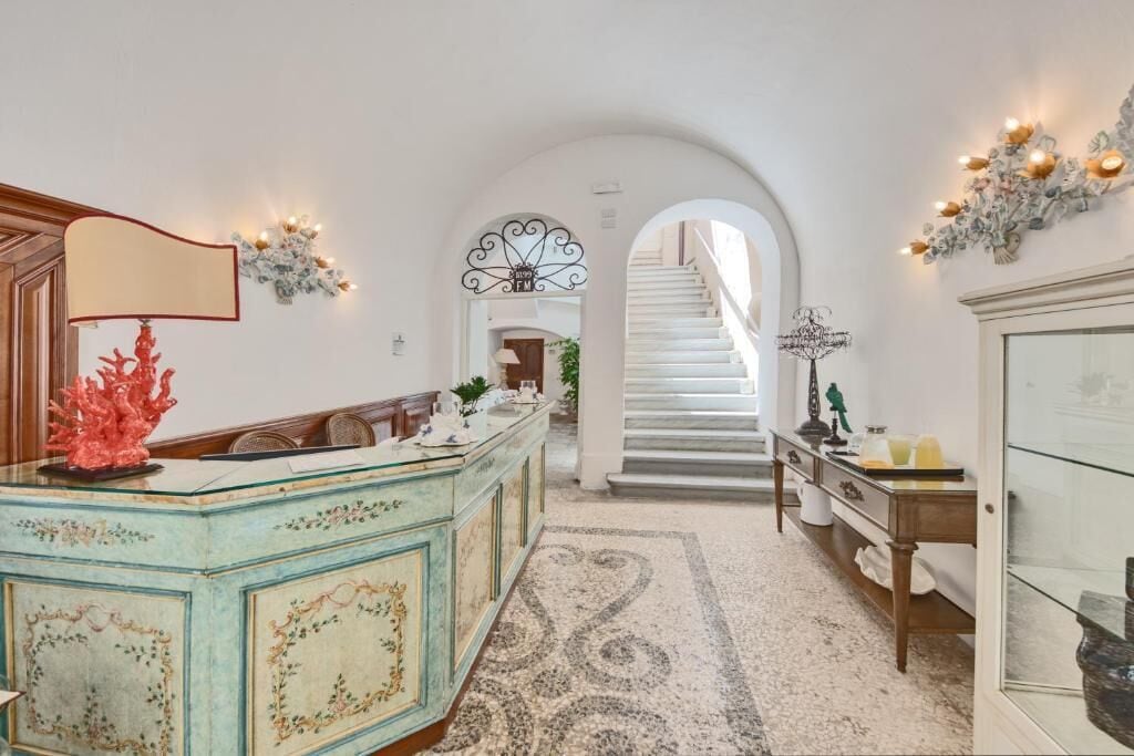 Una habitación amplia con una isla central, una escalera que sube a un nivel superior y un arco decorativo.