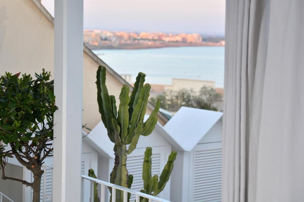 Een balkon met uitzicht op zee en gebouwen op de achtergrond.