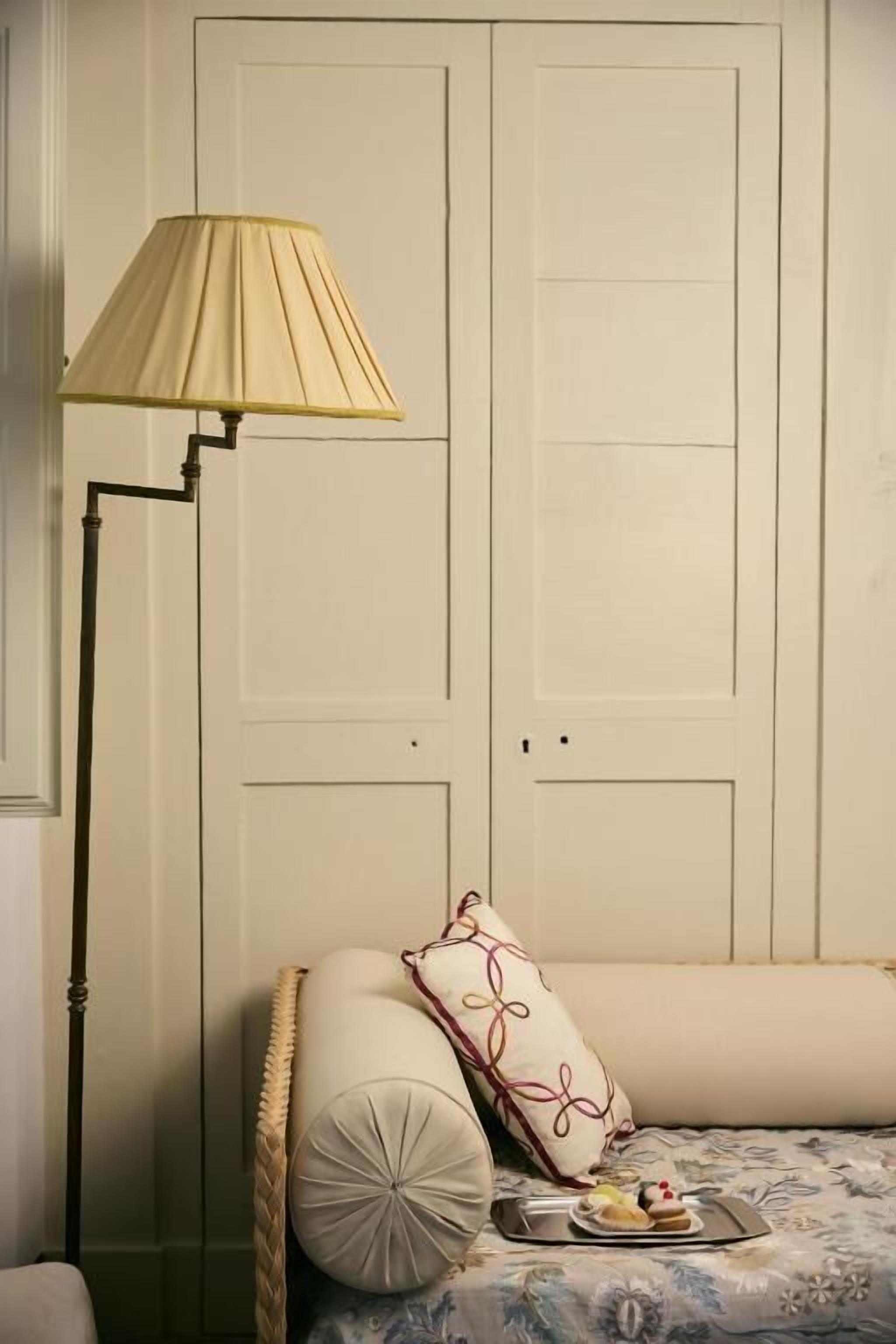 Une pièce avec un lit, une lampe de chevet et une porte.