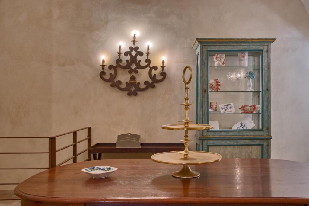 A dining table with a chandelier and a cabinet with glass doors.