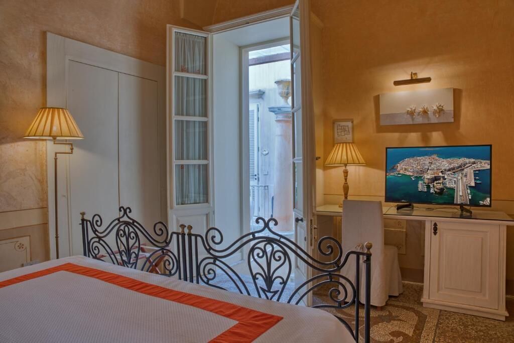 Une chambre d’hôtel avec un lit, une télévision et un bureau équipé d’une lampe.