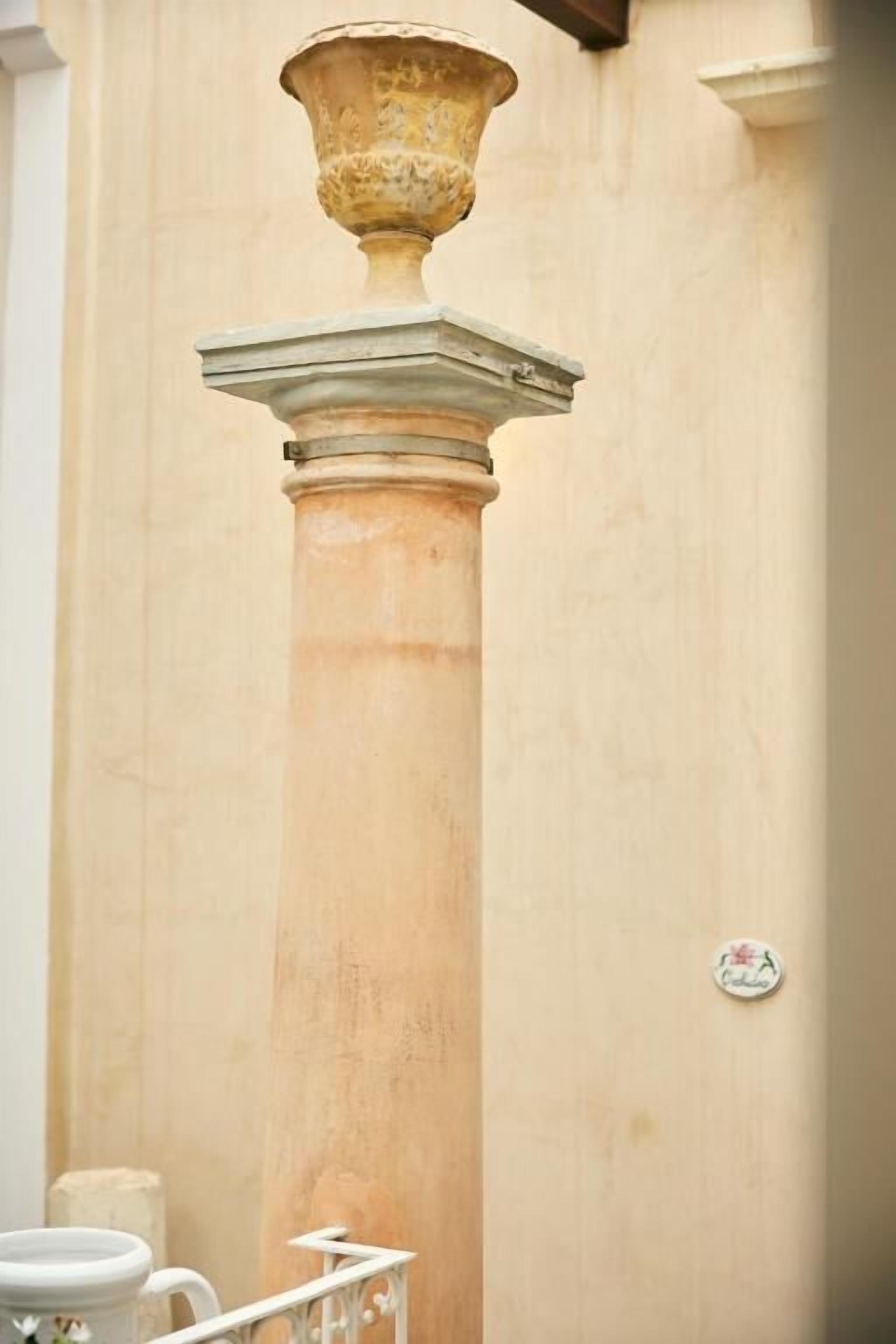 Un baño con una columna grande, un pedestal y un pequeño adorno en la pared.