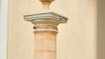 Un baño con una columna grande, un pedestal y un pequeño adorno en la pared.