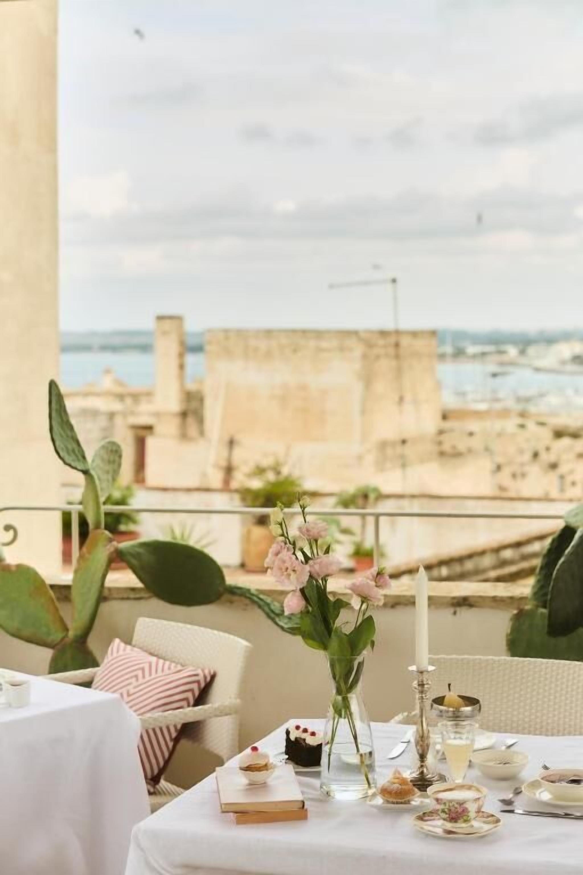 Una mesa de comedor dispuesta con comida y bebidas, con vistas a la costa.