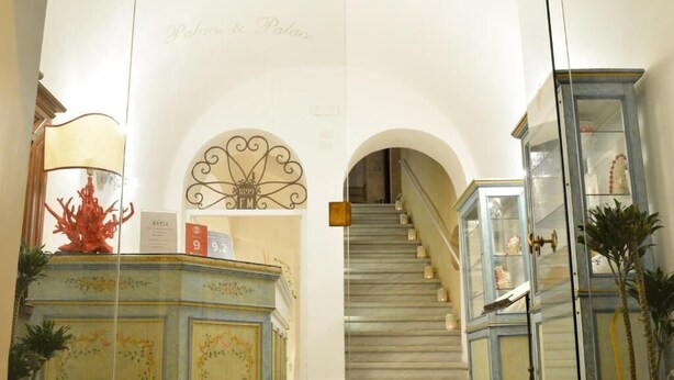 Eine prachtvolle Treppe führt zu einer oberen Etage, gesäumt von verzierten Schränken und einer dekorativen Decke.