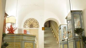 A grand staircase leading to an upper floor, flanked by ornate cabinets and a decorative ceiling.