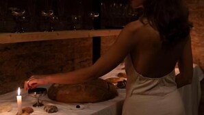 A person in a white dress at a table with a lit candle, bread, and wine glasses. - Palazzo Mosco  (Gallipoli)