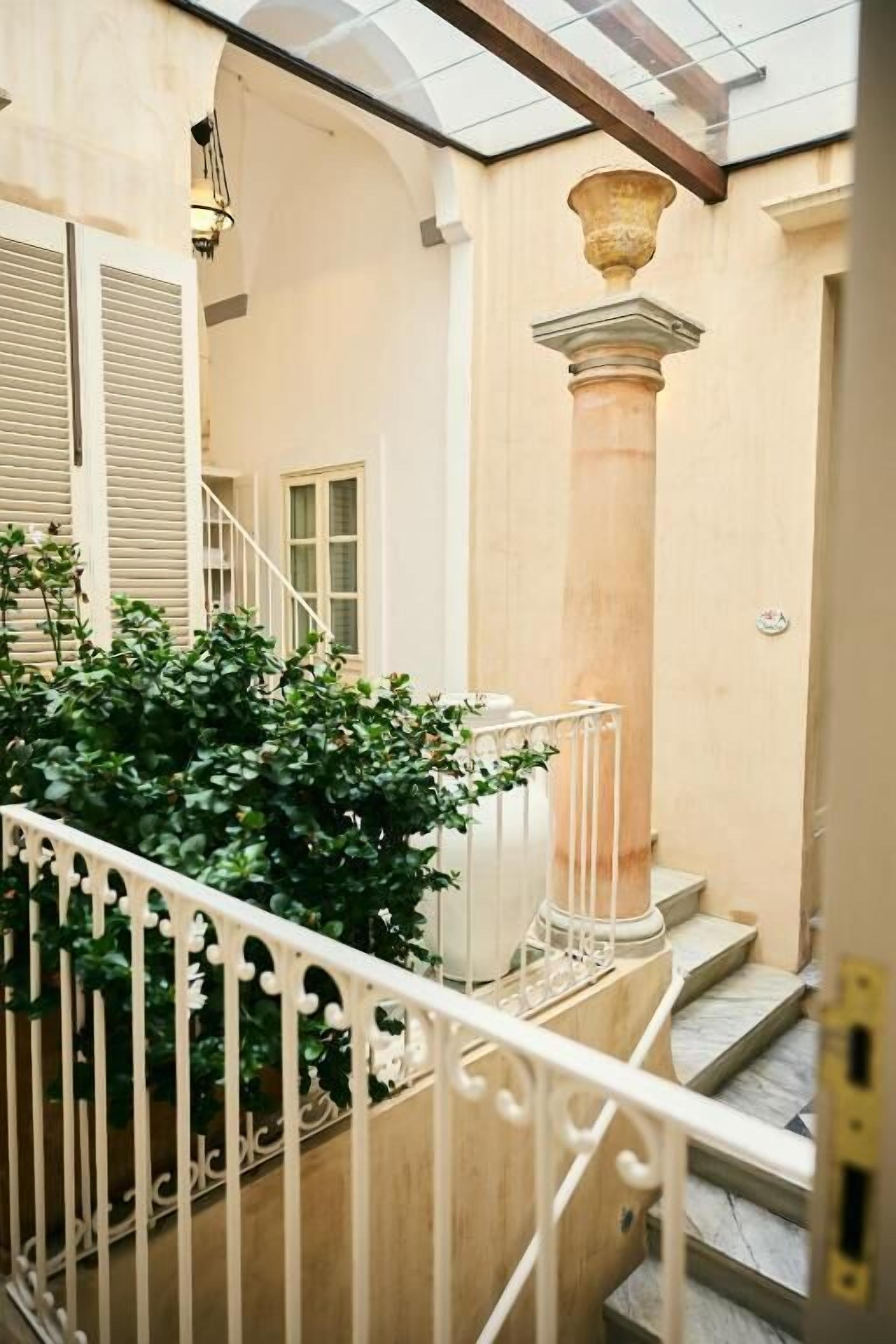 Un escalier avec une balustrade blanche, une colonne et une plante en pot.