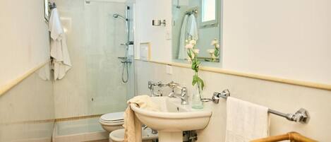 Baño con ducha, inodoro, lavabo y espejo.