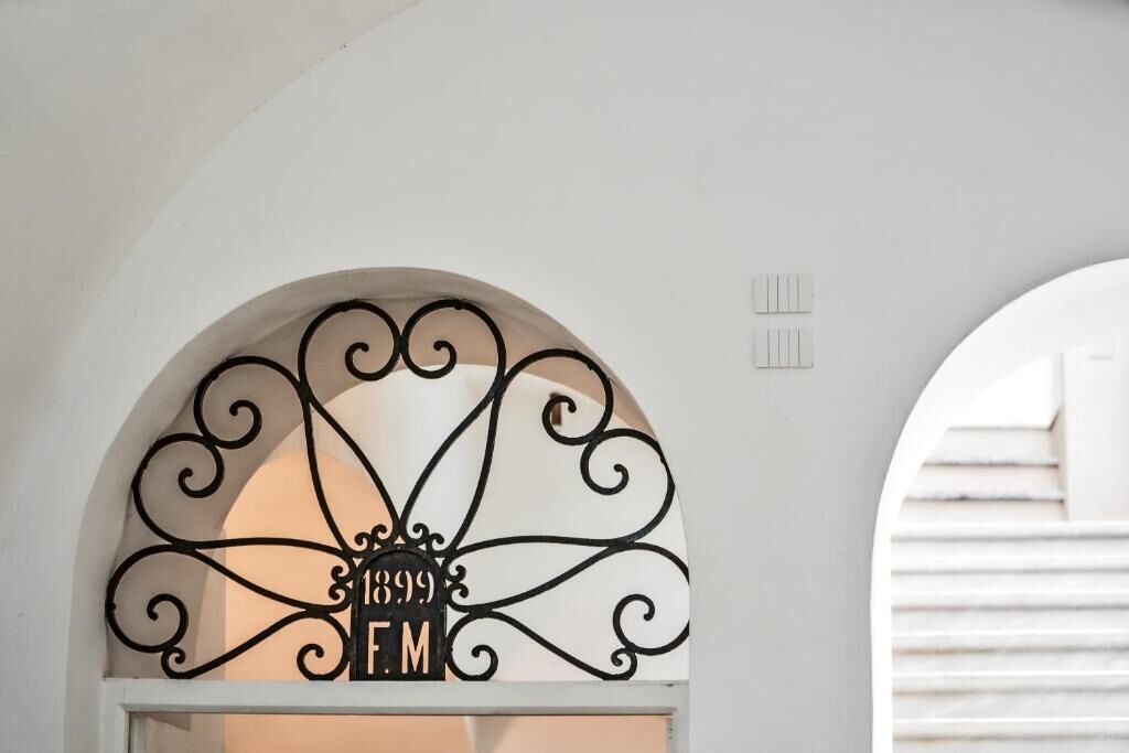 A white arched doorway with a decorative metal sign reading "1899 EM" and a small ventilation vent above it.