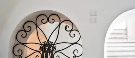 A white arched doorway with a decorative metal sign reading "1899 EM" and a small ventilation vent above it.