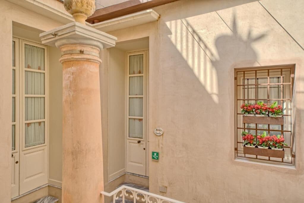 Un edificio con una columna, una puerta y una ventana adornada con macetas de flores.