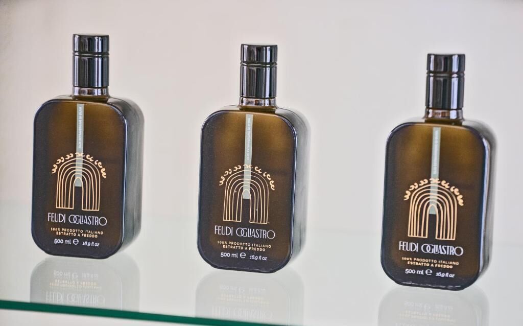 Three identical bottles of Feudi Cogliastro Italian extra virgin olive oil.