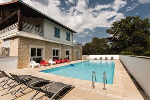 A swimming pool with lounge chairs and a stone building with a balcony. - Garden & City Lyon Lissieu (Lissieu)
