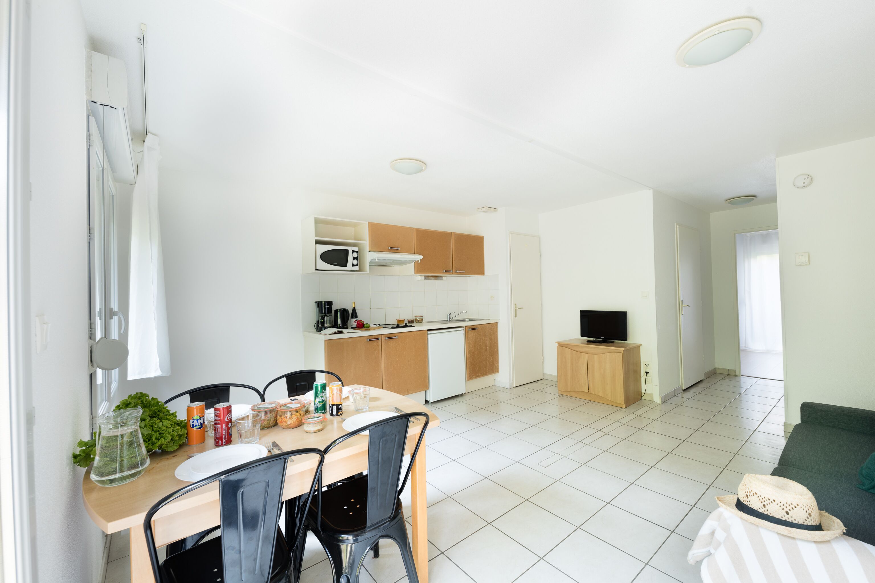 A modern, well-lit room with a dining area, kitchenette, and a living space.