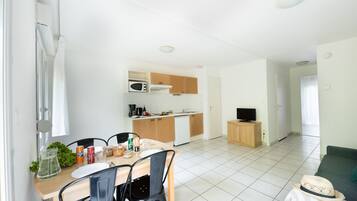 A modern, well-lit room with a dining area, kitchenette, and a living space.