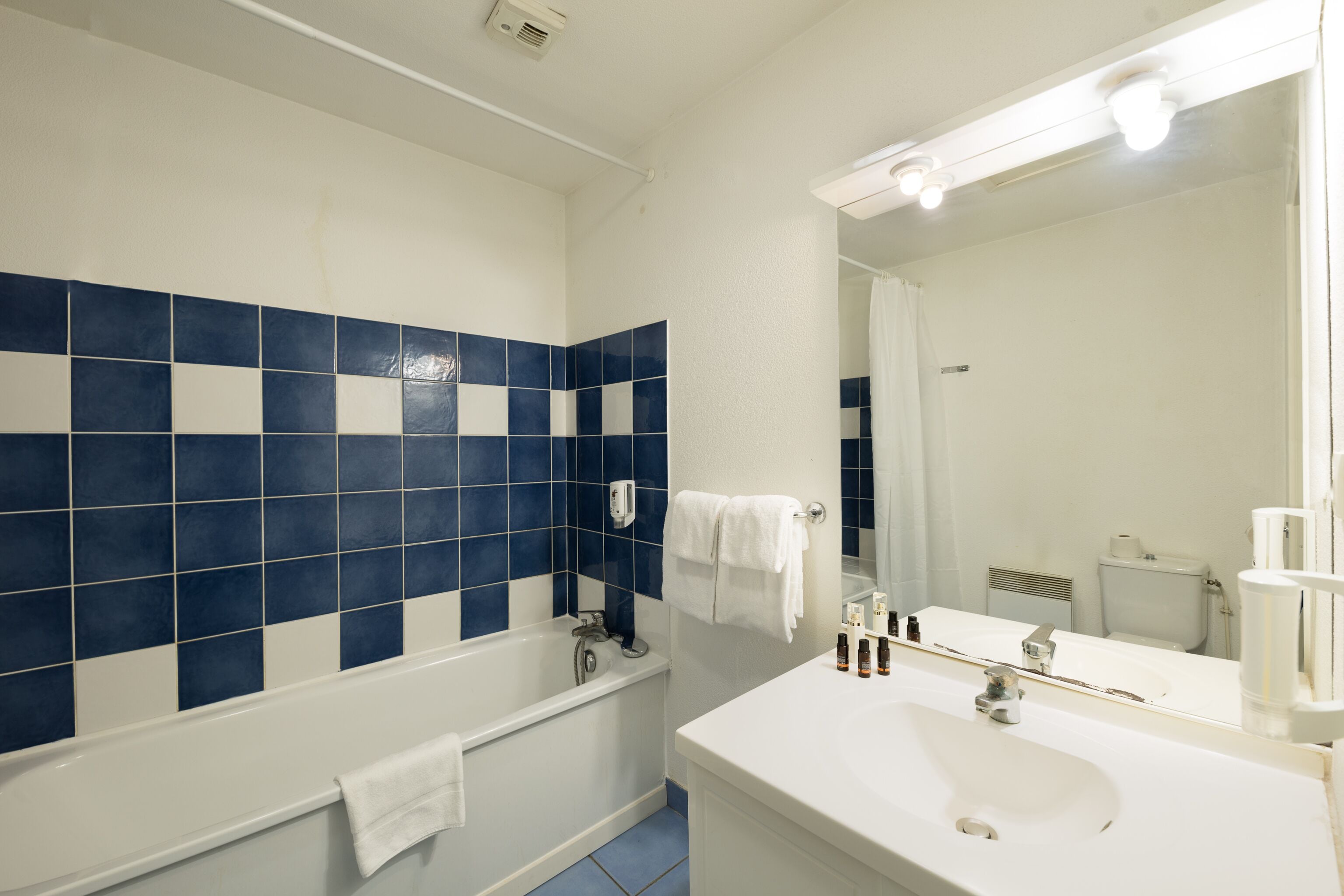 A bathroom with a bathtub, a sink, and a mirror.