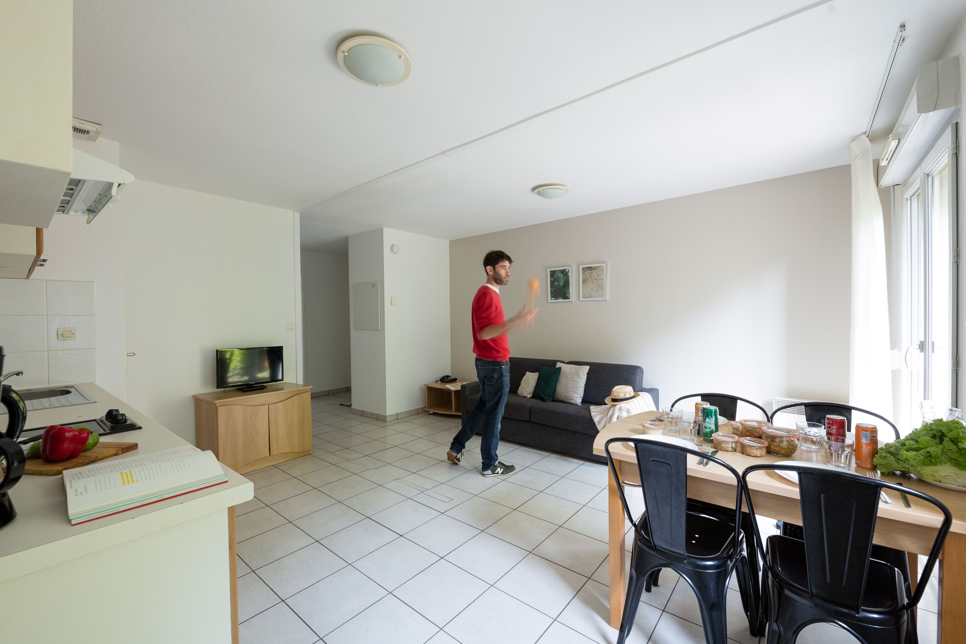 Una cocina moderna con comedor, televisión y sofá.
