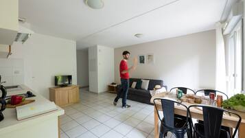 A modern kitchen with a dining area, a television, and a sofa.