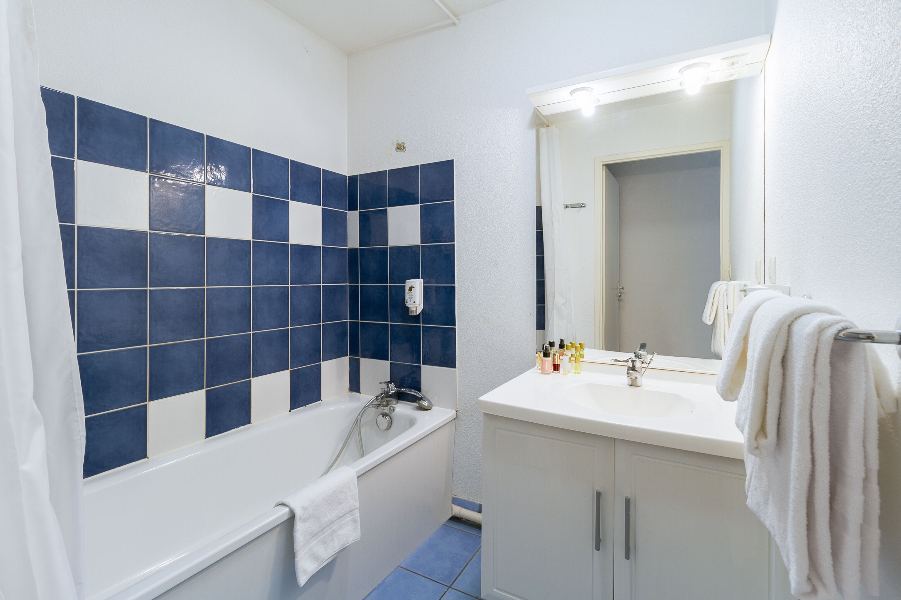A bathroom with a bathtub, a sink, and a mirror.